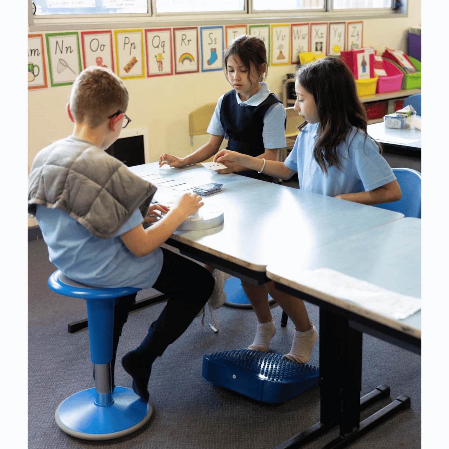 Boy sitting on Sensory Specialist wriggle stool with shoulder wrap