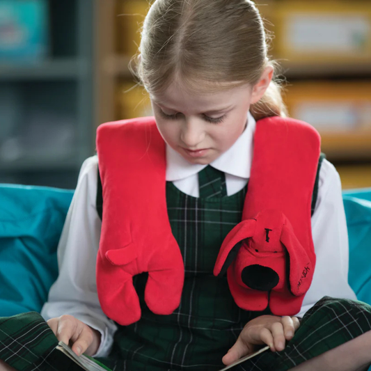 Calming shoupder pad in shape of red dog on a young girl in school uniform