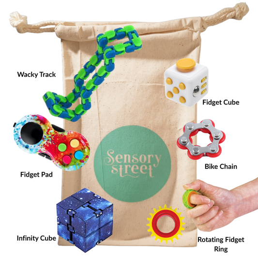 A sensory toy set displayed on a beige drawstring bag with the brand name 'Sensory Street' printed on the front. The set includes a wacky track chain, fidget cube, fidget pad, bike chain, infinity cube, and rotating fidget ring.