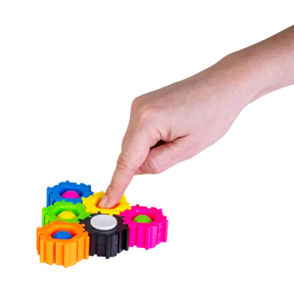 Colorful gear puzzle toy with a hand interacting with it on a white background