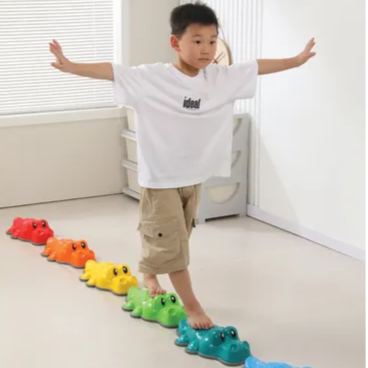 boy balancing on crocodile shaped stepping stones in a line
