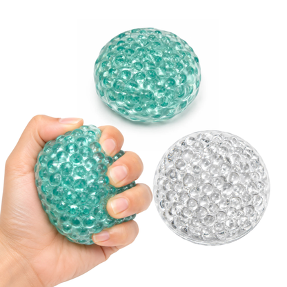 three glass bead balls, round squishy bead balls. one hand crunching it.